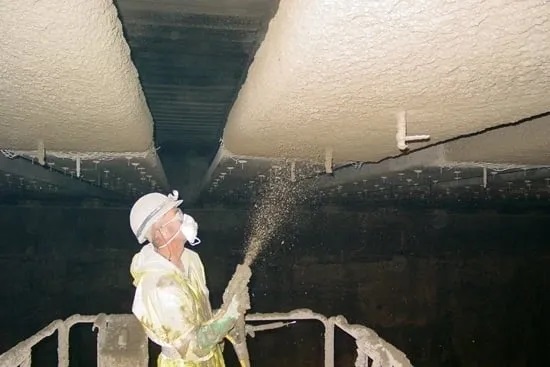 A construction worker putting cement on a ceiling